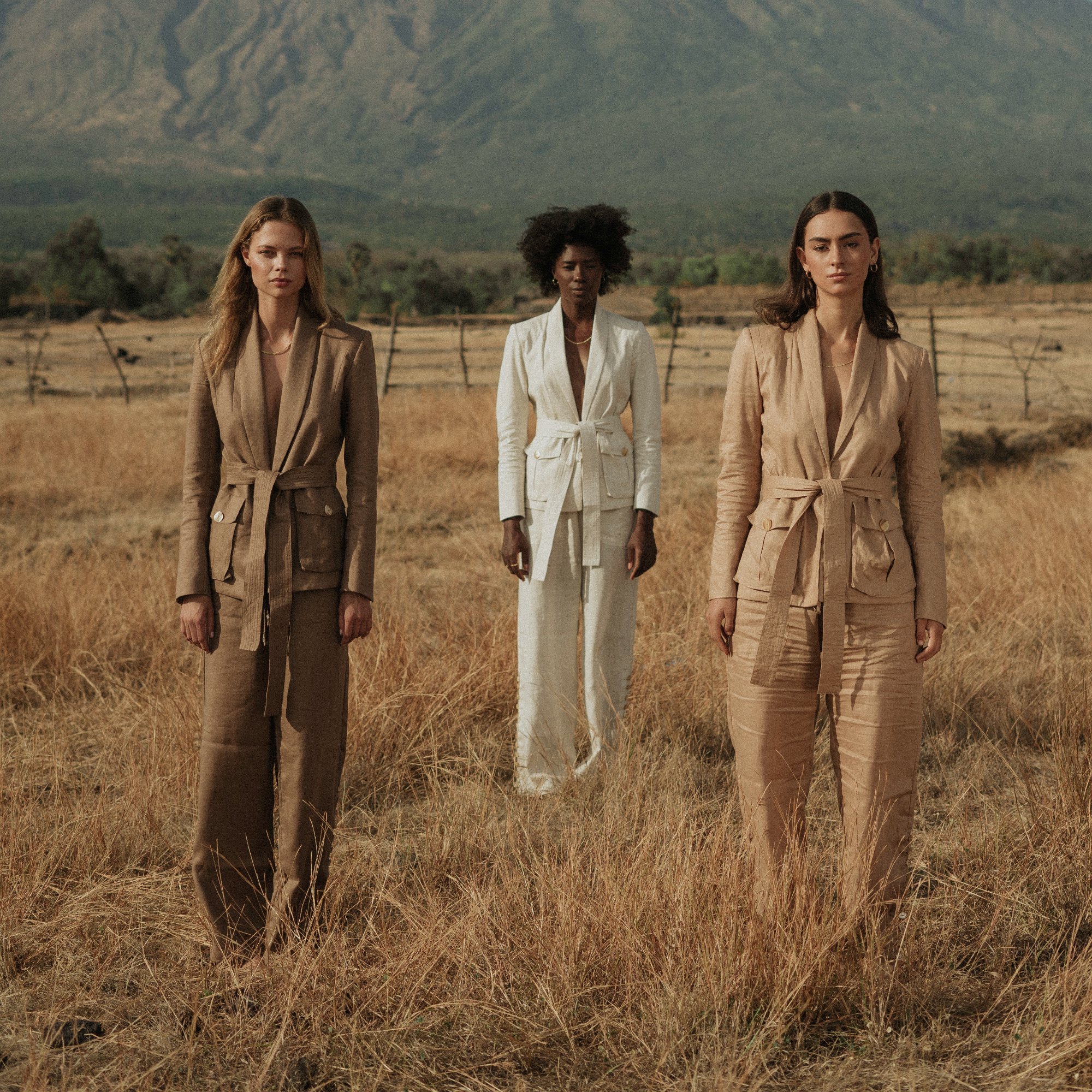 Three women in linen suiting in an open field